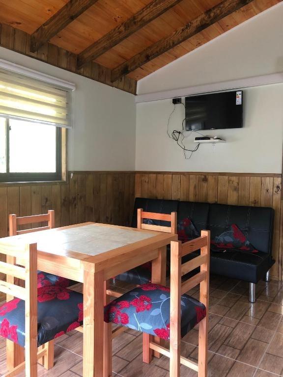 Comedor de madera con televisión y sofá dentro de la cabaña