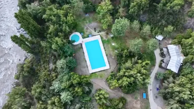 Vista aérea de dos piscinas entre árboles junto al río