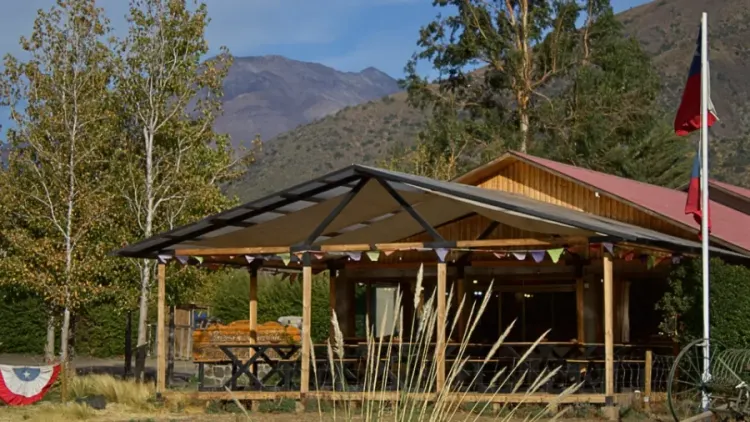 Construcción de madera con terraza cubierta y montañas al fondo